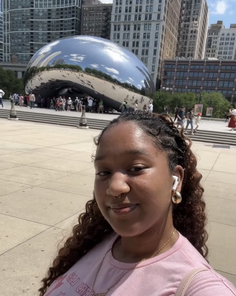 Kymari smiling in front of Cloud Gate, the mirrored Bean sculpture in Chicago